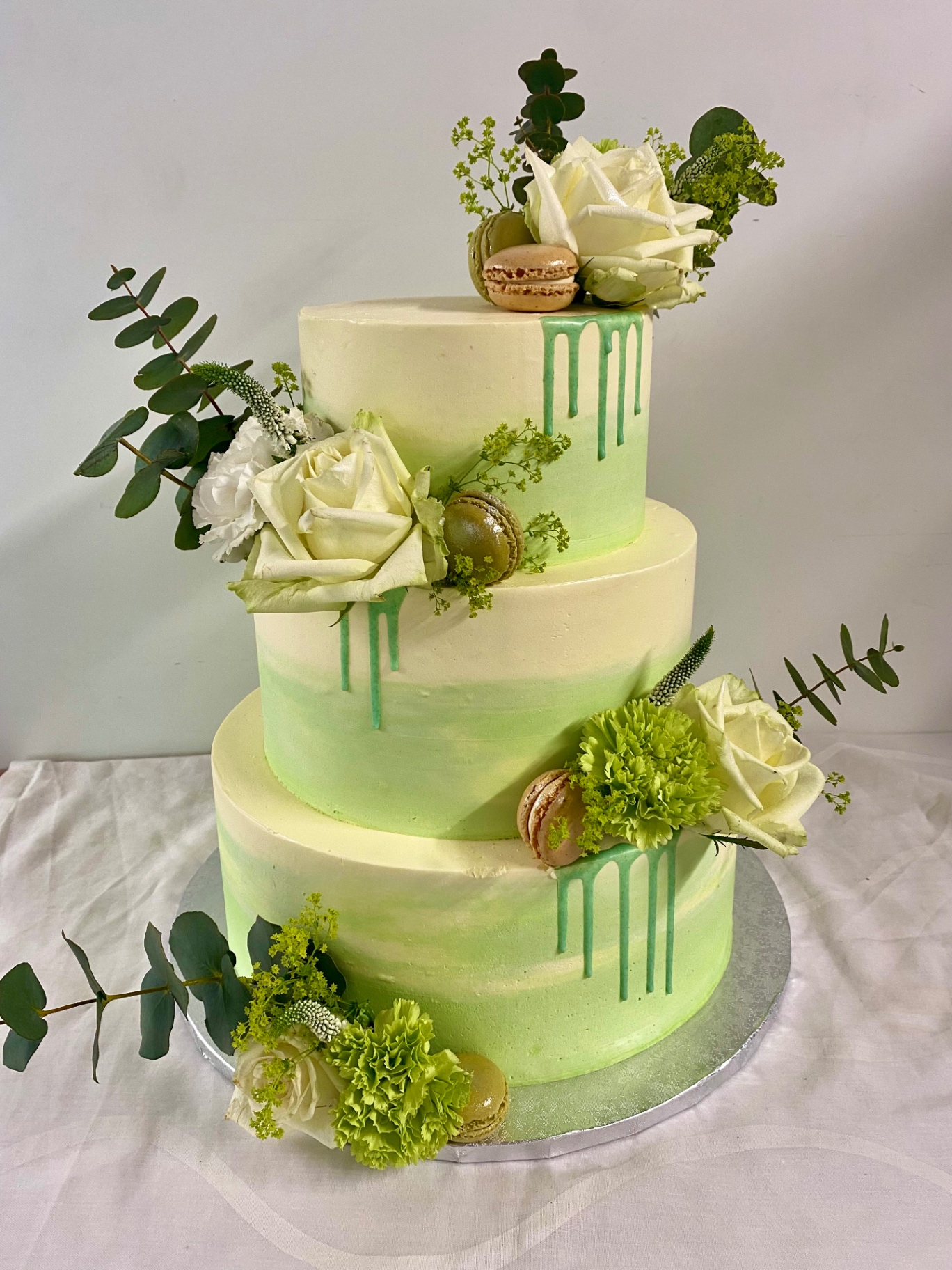 Mint-Drip — Dreistöckig mit grünem Aquarell-Verlauf, Mint-Drip, weißen Rosen, Eukalyptus und Macarons.. Hochzeitstorte aus Lauras Tortenmanufaktur, Meitzendorf bei Magdeburg.