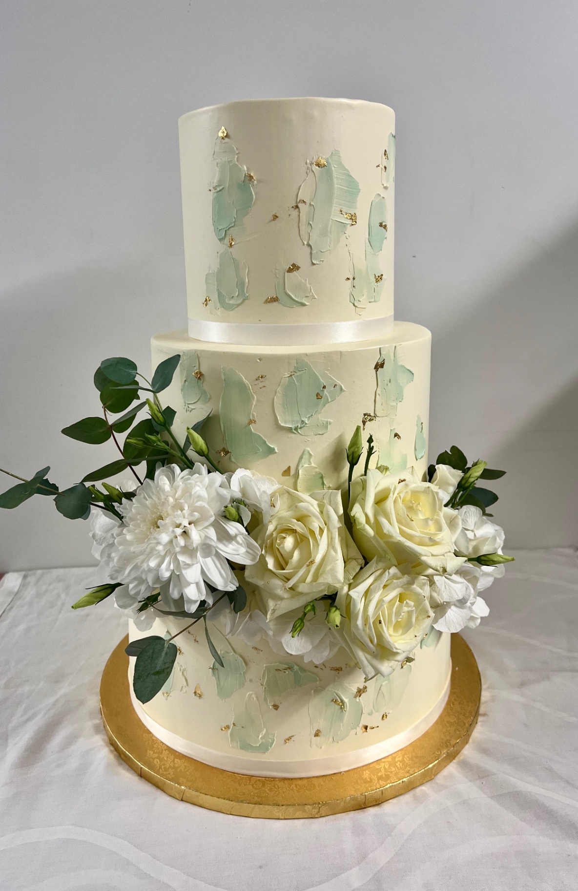 Mint & Gold — Zweistöckig mit Mint-Brushstrokes, Blattgold und weißem Rosenbouquet.. Hochzeitstorte aus Lauras Tortenmanufaktur, Meitzendorf bei Magdeburg.