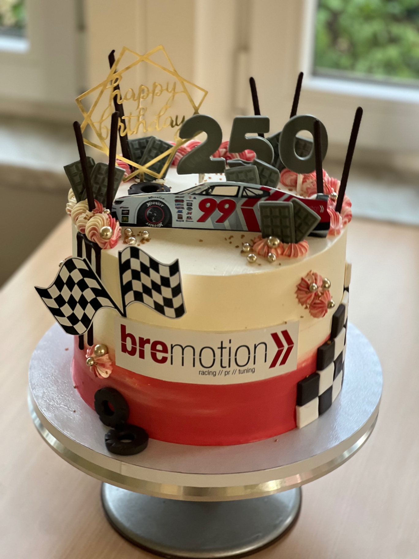 bremotion — 250 — Weiß und Rot mit Zielflaggen, Rennauto Nr. 99 und Mikadostäbchen.. Motivtorte aus Lauras Tortenmanufaktur, Meitzendorf bei Magdeburg.